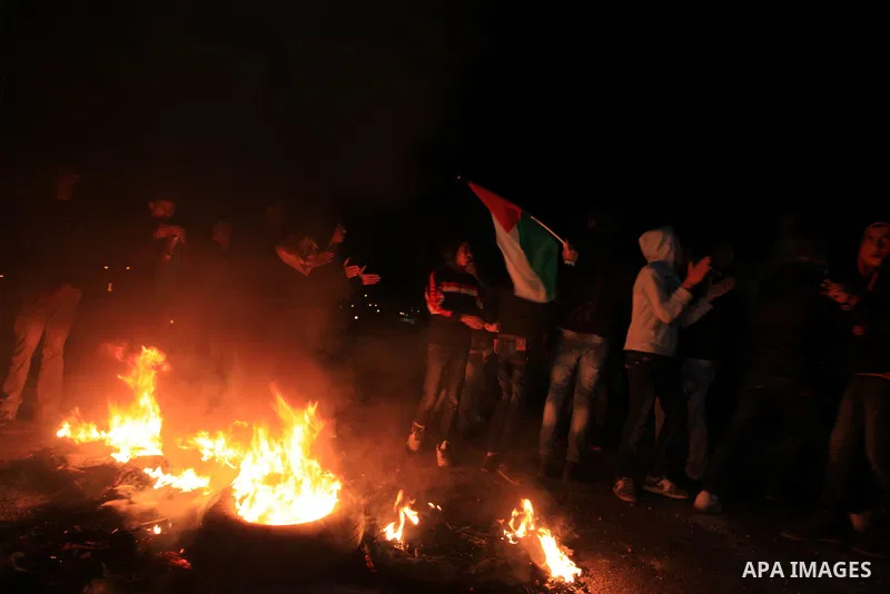 Palestinian protesters roll a tire into a fire to erect a barricade during clashes with Israeli security forces following the killing of Palestinian Waji al-Ramhi, in the West Bank city of Ramallah on December 7, 2013. I...