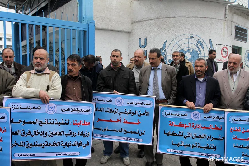 Palestinians hold banners during a protest against the UNRWA decision reduce salaries in front of the headquarters United Nations Relief and Works Agency (UNRWA) in Gaza city, on Dec. 10, 2013. Photo by Mohammed Asad