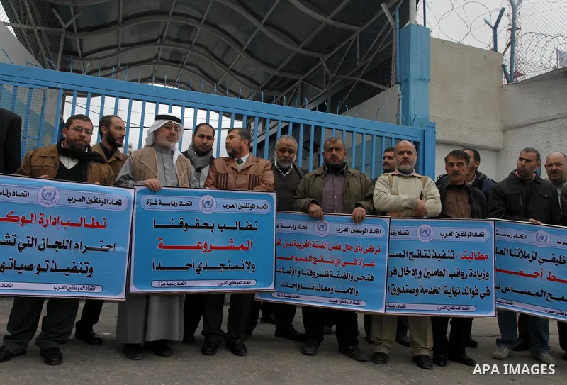 Palestinians hold banners during a protest against the UNRWA decision reduce salaries in front of the headquarters United Nations Relief and Works Agency (UNRWA) in Gaza city, on Dec. 10, 2013. Photo by Mohammed Asad