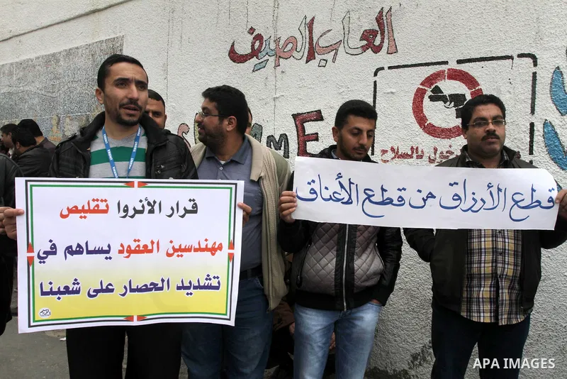 Palestinians hold banners during a protest against the UNRWA decision reduce salaries in front of the headquarters United Nations Relief and Works Agency (UNRWA) in Gaza city, on Dec. 10, 2013. Photo by Mohammed Asad