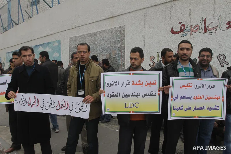Palestinians hold banners during a protest against the UNRWA decision reduce salaries in front of the headquarters United Nations Relief and Works Agency (UNRWA) in Gaza city, on Dec. 10, 2013. Photo by Mohammed Asad