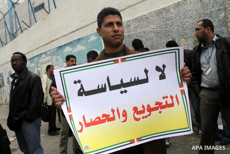 Palestinians hold banners during a protest against the UNRWA decision reduce salaries in front of the headquarters United Nations Relief and Works Agency (UNRWA) in Gaza city, on Dec. 10, 2013. Photo by Mohammed Asad