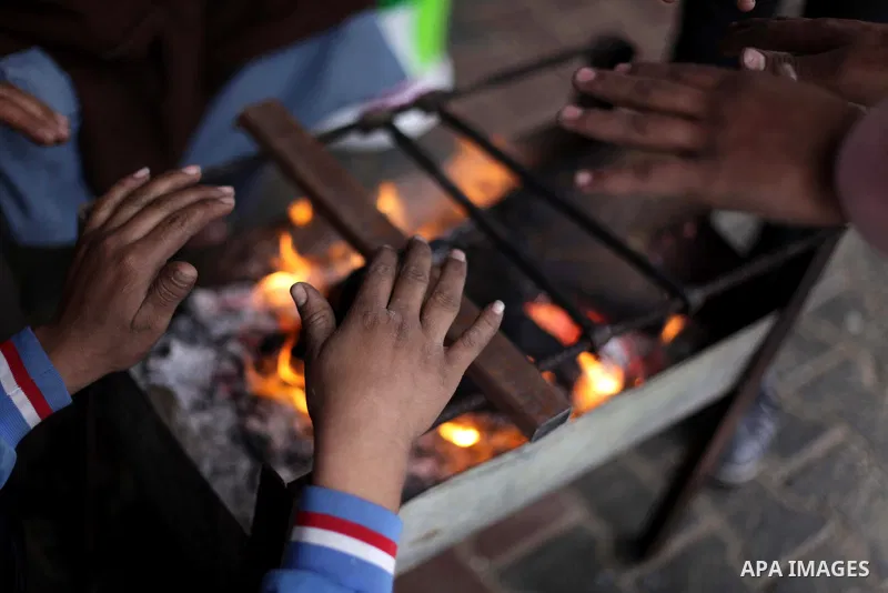 Palestinians warm themselves on firewood during heavy rains on a stormy day at Shati refugee camp in Gaza City, December 11, 2013. The Gaza Strip Power Authority is worried that electricity will be available for less tha...