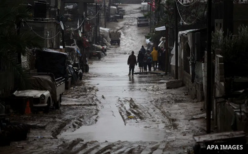 Palestinians walk in a flooded street during heavy rains on a stormy day in Gaza City, December 11, 2013. The Gaza Strip Power Authority is worried that electricity will be available for less than six hours a day in Gaza...