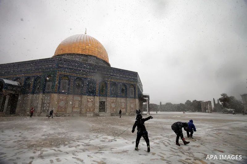 Palestinian children play in the snow in front of the Dome of the Rock at the Al-Aqsa mosques compound in the old city of Jerusalem on December 12, 2013 as a winter weather front hit the region, bringing early snow and a...