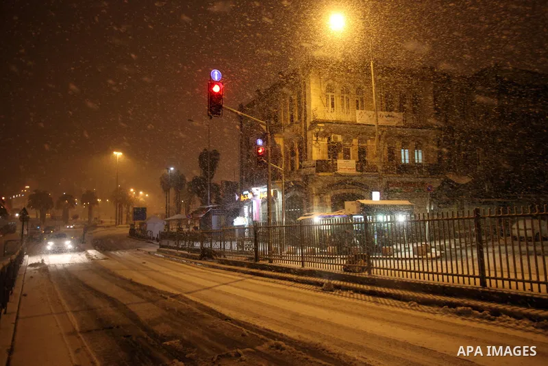 A car passes a street that coverd with snow during a snowstorm in Jerusalem's Old City on December 12, 2013. Jerusalem is covered with snow Thursday, the heaviest snow storm hitting the city since 1953 as meteorologists...
