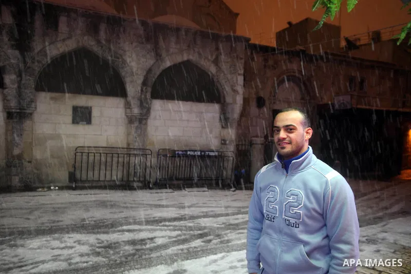 A Palestinian man poses for a photograph in a street that covered with snow during a snowstorm in Jerusalem's Old City on December 12, 2013. Jerusalem is covered with snow Thursday, the heaviest snow storm hitting the ci...