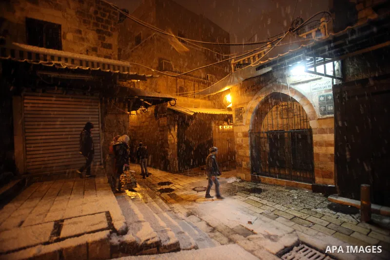 Palestinians walk in a street that covered with snow during a snowstorm in Jerusalem's Old City on December 12, 2013. Jerusalem is covered with snow Thursday, the heaviest snow storm hitting the city since 1953 as meteor...