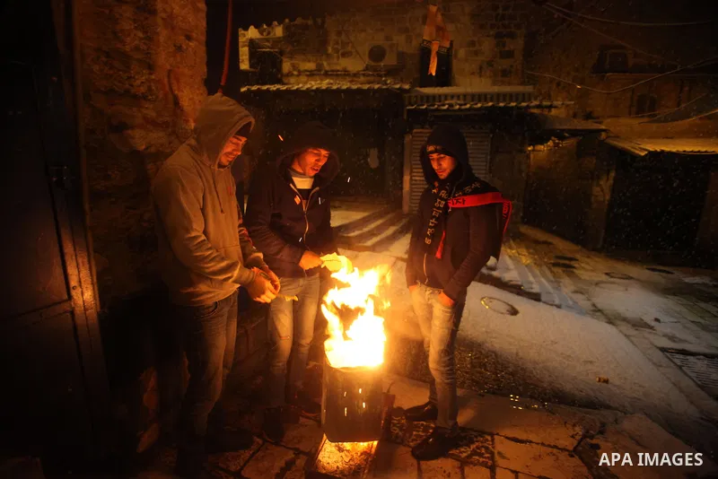 Palestinians use firewood to warm themselves during a snowstorm in Jerusalem's Old City on December 12, 2013. Jerusalem is covered with snow Thursday, the heaviest snow storm hitting the city since 1953 as meteorologists...