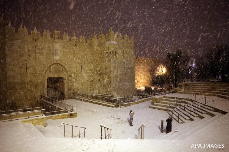 People take photos in front of Damascus gate during a snowstorm in Jerusalem's Old City on December 12, 2013. Jerusalem is covered with snow Thursday, the heaviest snow storm hitting the city since 1953 as meteorologists...