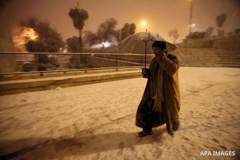 A Palestinian man walks in front of Damascus gate during a snowstorm in Jerusalem's Old City on December 12, 2013. Jerusalem is covered with snow Thursday, the heaviest snow storm hitting the city since 1953 as meteorolo...