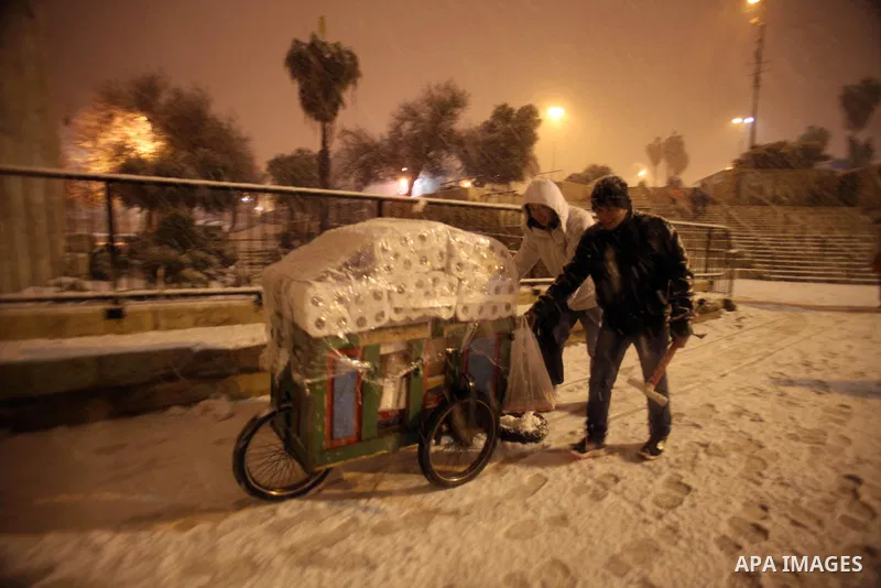 Palestinian vendors walk in front of Damascus gate during a snowstorm in Jerusalem's Old City on December 12, 2013. Jerusalem is covered with snow Thursday, the heaviest snow storm hitting the city since 1953 as meteorol...