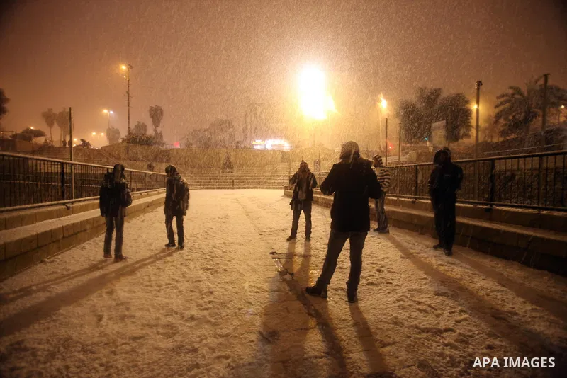 People walk in front of Damascus gate during a snowstorm in Jerusalem's Old City on December 12, 2013. Jerusalem is covered with snow Thursday, the heaviest snow storm hitting the city since 1953 as meteorologists dubbed...