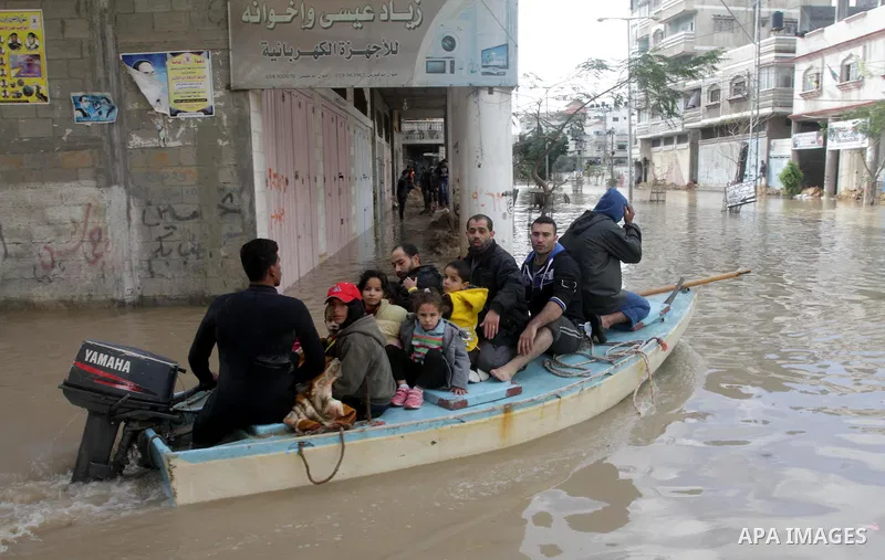 Members of the Palestinian civil defense evacuate people on a boat after their houses were flooded with rain water on a stormy day in Gaza City December 13, 2013. A severe winter deluge enveloping much of the Eastern Med...