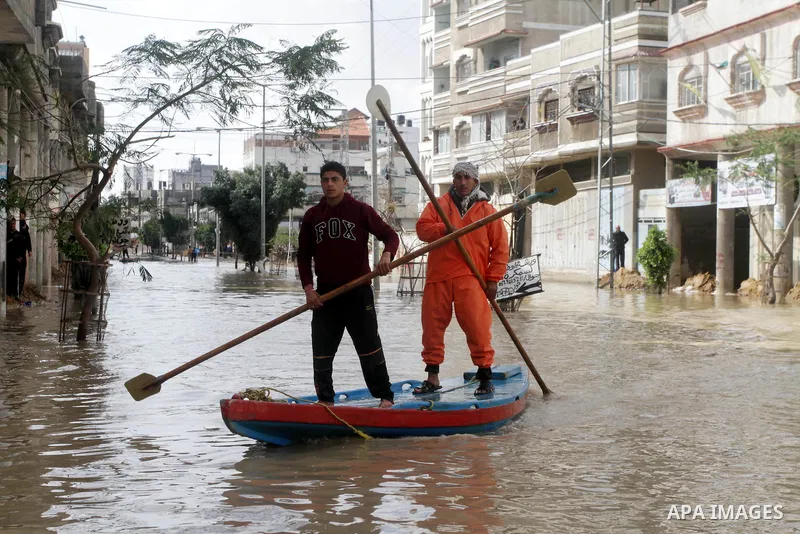 Members of the Palestinian civil defense evacuate people on a boat after their houses were flooded with rain water on a stormy day in Gaza City December 13, 2013. A severe winter deluge enveloping much of the Eastern Med...