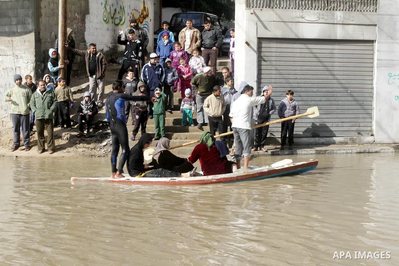 Members of the Palestinian civil defense evacuate people on a boat after their houses were flooded with rain water on a stormy day in Gaza City December 13, 2013. A severe winter deluge enveloping much of the Eastern Med...