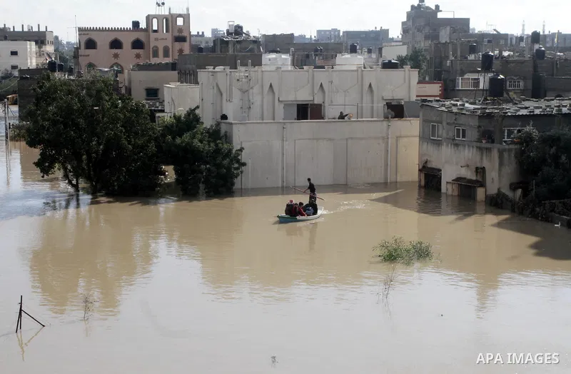 Members of the Palestinian civil defense evacuate people on a boat after their houses were flooded with rain water on a stormy day in Gaza City December 13, 2013. A severe winter deluge enveloping much of the Eastern Med...