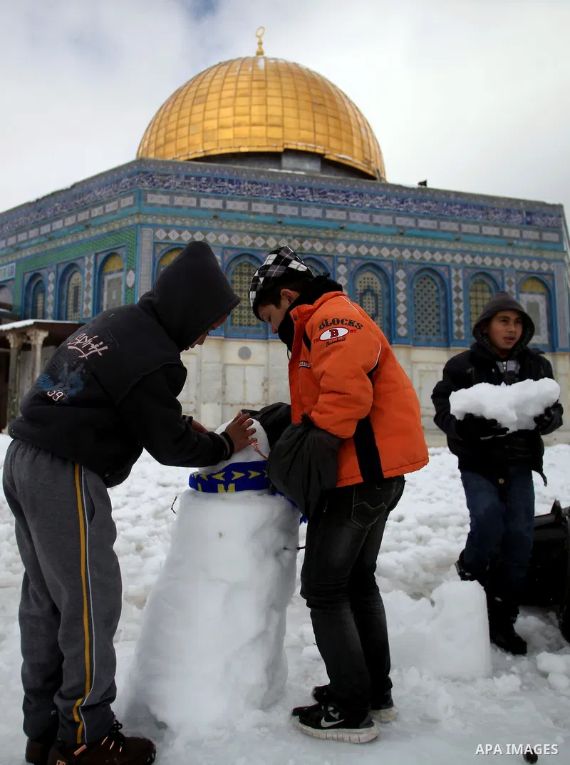 Palestinian children play with snow in front of the Dome of the Rock mosque in Jerusalem's Old City following a snowstorm on December 13, 2013. The hilltop city of Jerusalem was paralysed today by its fiercest snowstorm...