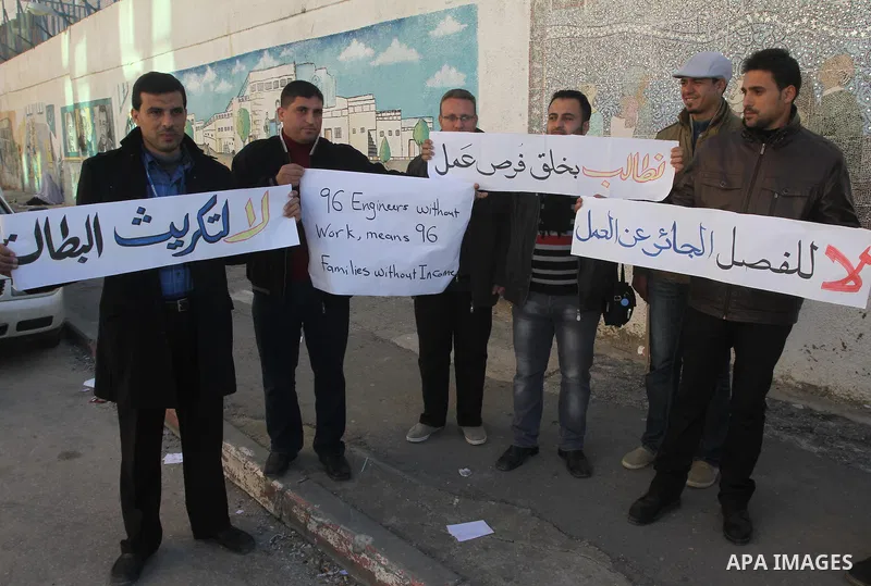 Palestinian engineers hold banners during a protest against the UNRWA decision to reduce of the work contracts in front of the headquarters United Nations Relief and Works Agency (UNRWA) in Gaza city, on Dec. 17, 2013. P...