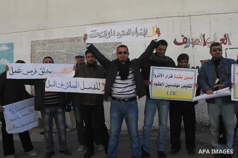 Palestinian engineers hold banners during a protest against the UNRWA decision to reduce of the work contracts in front of the headquarters United Nations Relief and Works Agency (UNRWA) in Gaza city, on Dec. 17, 2013. P...