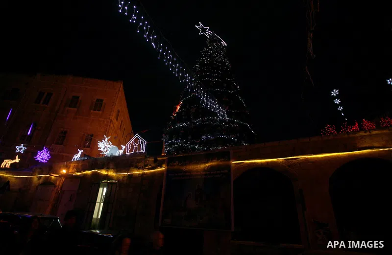 People walk in front of Christmas tree, in Jerusalem's Old City, December 25, 2013. Photo by Saeed Qaq