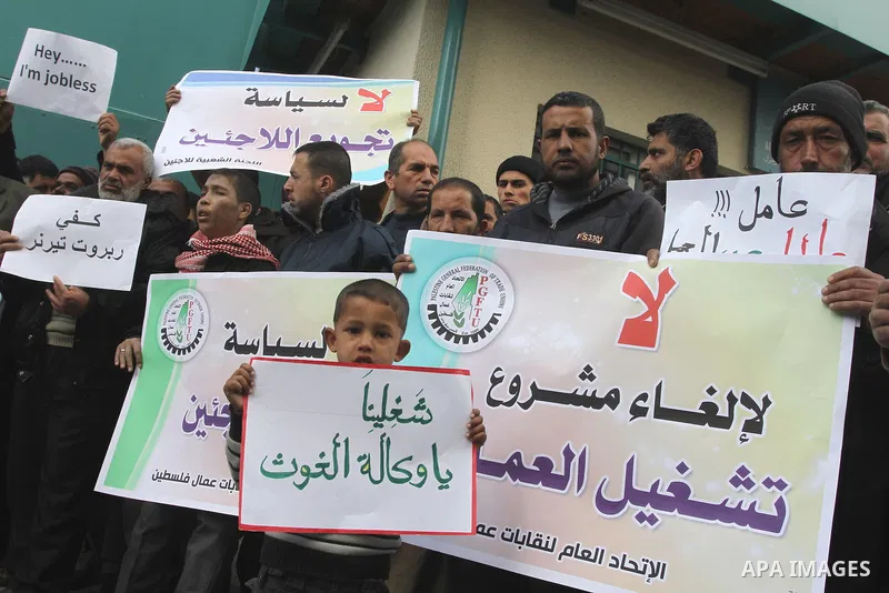 Palestinians hold banners during a protest against the UNRWA decision to reduce of the work contracts in front of the headquarters United Nations Relief and Works Agency (UNRWA) in Gaza city, on Dec. 26, 2013. Photo by M...