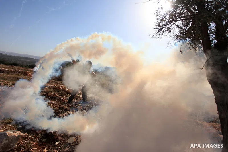 A Palestinian protester uses a slingshot to hurl back a tear gas canister fired by Israeli soldiers during clashes following a weekly demonstration against Jewish settlements in the West Bank village of Bilin, near Ramal...