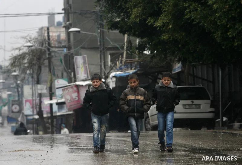 Palestinians walk under the rain, in Rafah Gaza Strip, on Dec. 31, 2013. Photo by Eyad Al Baba