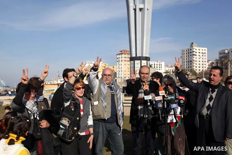 Members of Italian activists delegation flash victory signs during a visit to the Gaza seaport, in Gaza City on January 07, 2014. The Italian delegation had been visiting the Gaza Strip since Thursday evening, to express...