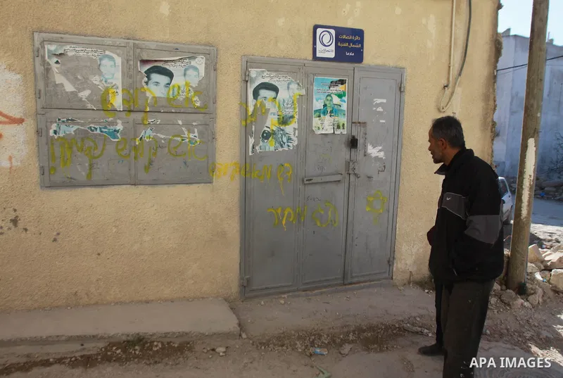 A Palestinian man looks at graffiti sprayed in Hebrew calling for revenge, in the village of Madama, on January 8, 2014, the day after Palestinians beat and detained several Israeli settlers who had entered the village o...
