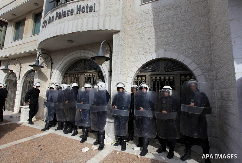 Riot police stand guard as Palestinian protesters demonstrate outside a hotel where a group of Israeli and Palestinian peace activists hold a meeting in the West Bank city of Ramallah, Thursday, Jan. 9, 2014. Protesters...