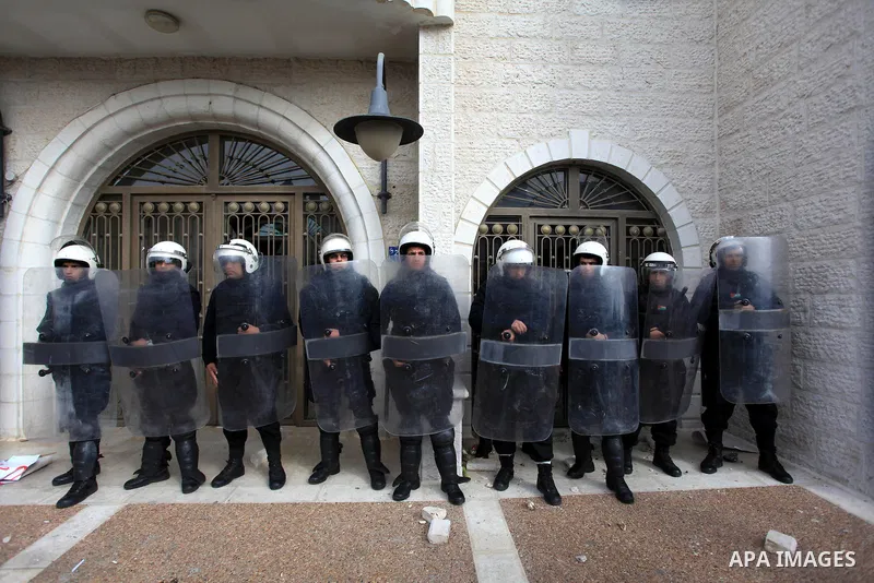 Riot police stand guard as Palestinian protesters demonstrate outside a hotel where a group of Israeli and Palestinian peace activists hold a meeting in the West Bank city of Ramallah, Thursday, Jan. 9, 2014. Protesters...