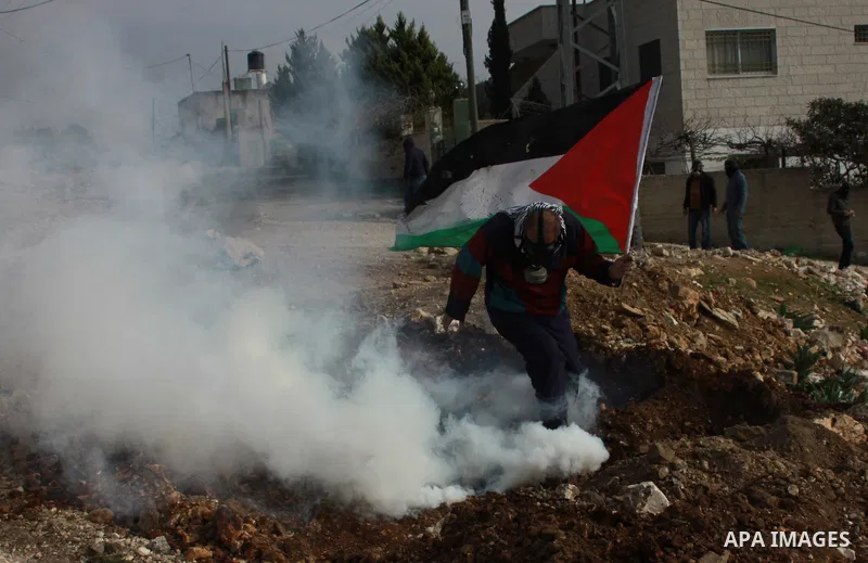 A Palestinian protester runs for cover from tear gas fired by Israeli security forces as clashes broke out during a demonstration against the expropriation of Palestinian land by Israel in the village of Kfar Qaddum, nea...