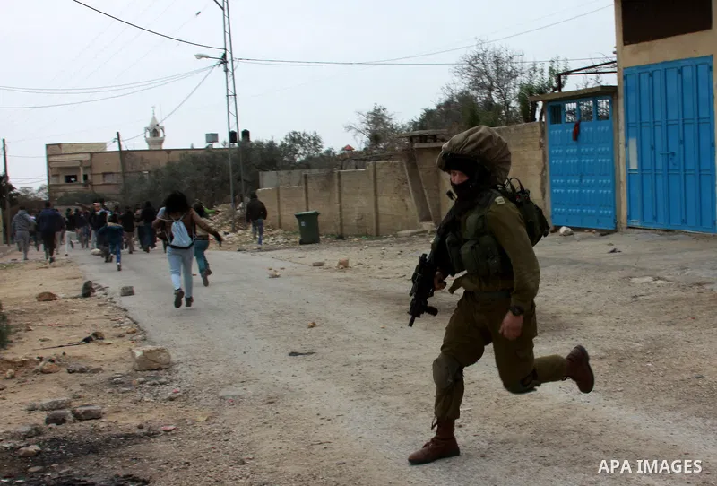 An Israeli security officer runs after Palestinian protesters as clashes broke out during a demonstration against the expropriation of Palestinian land by Israel in the village of Kfar Qaddum, near the occupied West Bank...