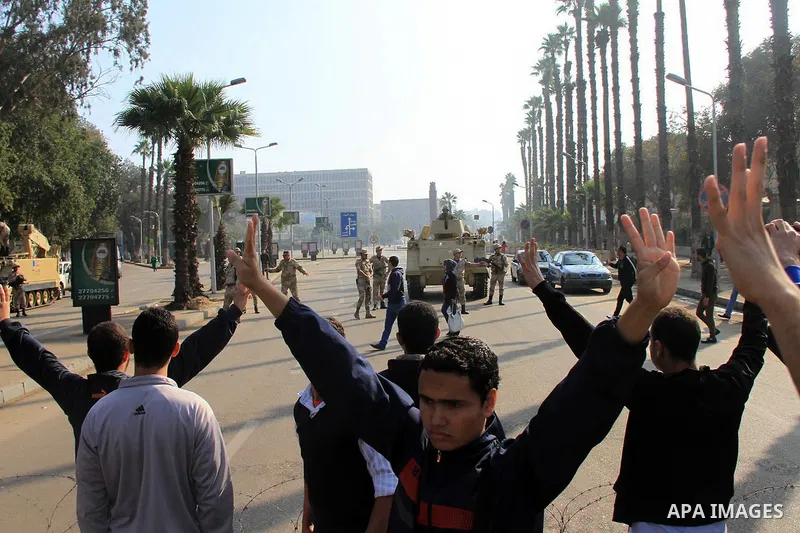 Students of Cairo University, who are supporters of the Muslim Brotherhood and deposed Egyptian President Mohamed Mursi, rise four fingers which has become a symbol of the Rabaah al-Adawiya mosque in front of security fo...