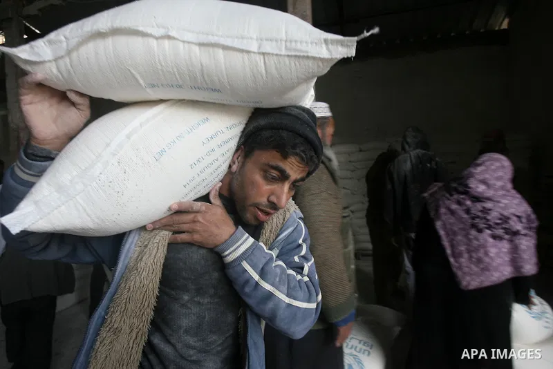 A Palestinian man holds a sack of flour at monthly food aid at a UN distribution center in Rafah southern Gaza city, on Jan. 11, 2014. The UN Relief and Works Agency (UNRWA) will reduce some of its services for Palestini...