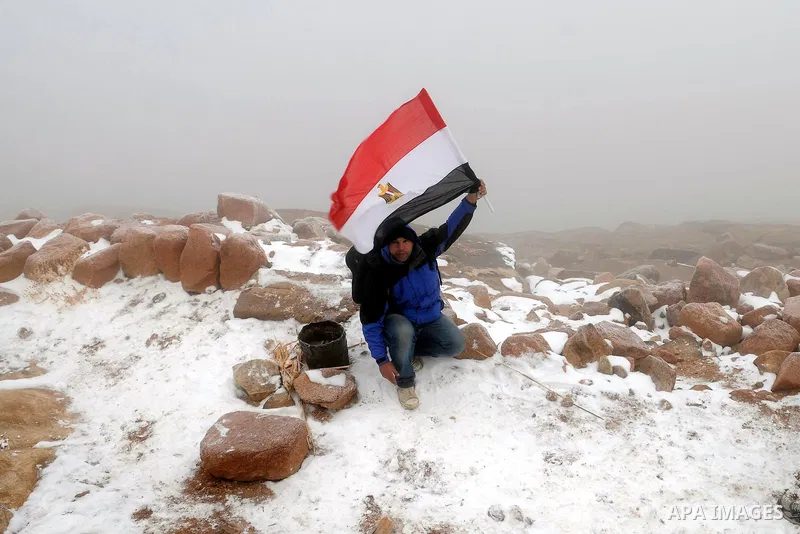 An Egyptian man holds his national flag as snow covers the Saint Catherine, south Sinai on January 13, 2014. Photo by Mohammed Bendari