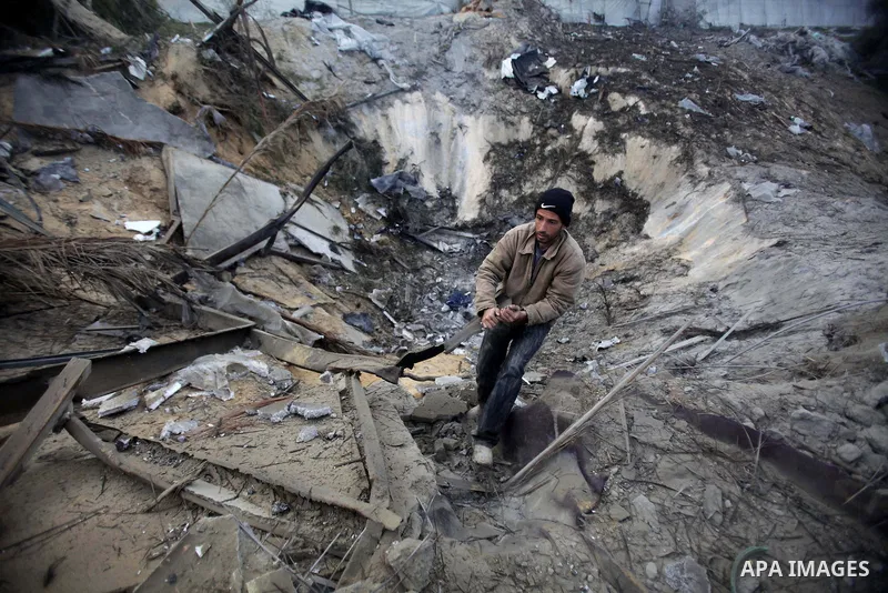 A Palestinian man inspects damage at a training site for the Al-Quds Brigades, the military wing of Islamic Jihad on January 14, 2014 after it was hit by an Israeli air strike in Khan Younis in the southern Gaza Strip th...