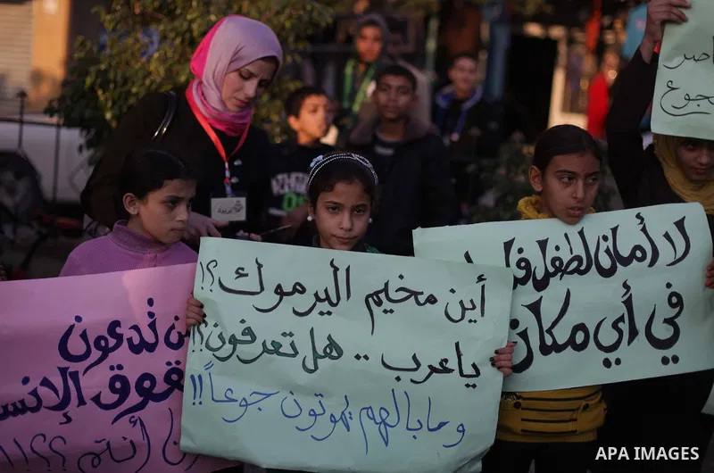 Palestinian children hold placards as they take part in a rally to show solidarity with Palestinian refugees in Syria's main refugee camp Yarmouk, in Deir al-Balah in the central Gaza Strip January 15, 2014. Photo by Ash...