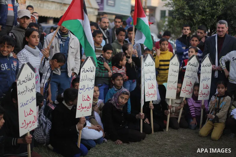 Palestinian children hold placards as they take part in a rally to show solidarity with Palestinian refugees in Syria's main refugee camp Yarmouk, in Deir al-Balah in the central Gaza Strip January 15, 2014. Photo by Ash...