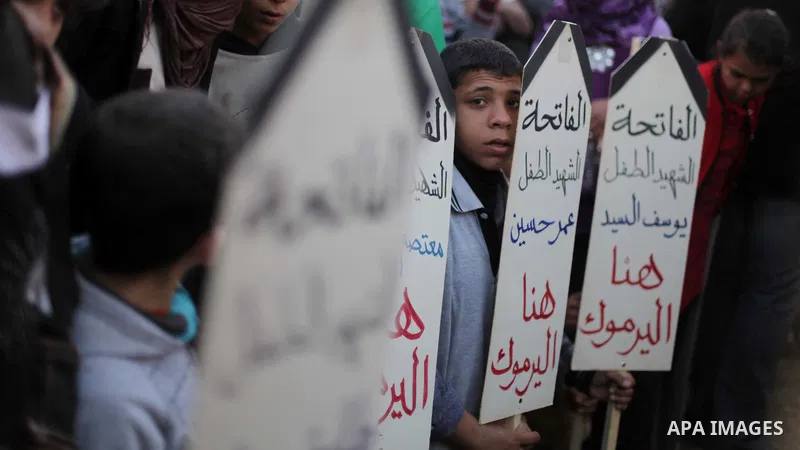 Palestinian children hold placards as they take part in a rally to show solidarity with Palestinian refugees in Syria's main refugee camp Yarmouk, in Deir al-Balah in the central Gaza Strip January 15, 2014. Photo by Ash...