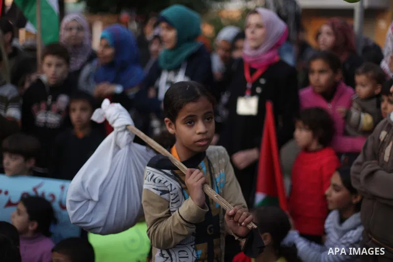 Palestinian children hold placards as they take part in a rally to show solidarity with Palestinian refugees in Syria's main refugee camp Yarmouk, in Deir al-Balah in the central Gaza Strip January 15, 2014. Photo by Ash...