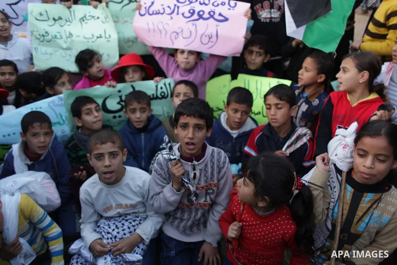 Palestinian children hold placards as they take part in a rally to show solidarity with Palestinian refugees in Syria's main refugee camp Yarmouk, in Deir al-Balah in the central Gaza Strip January 15, 2014. Photo by Ash...