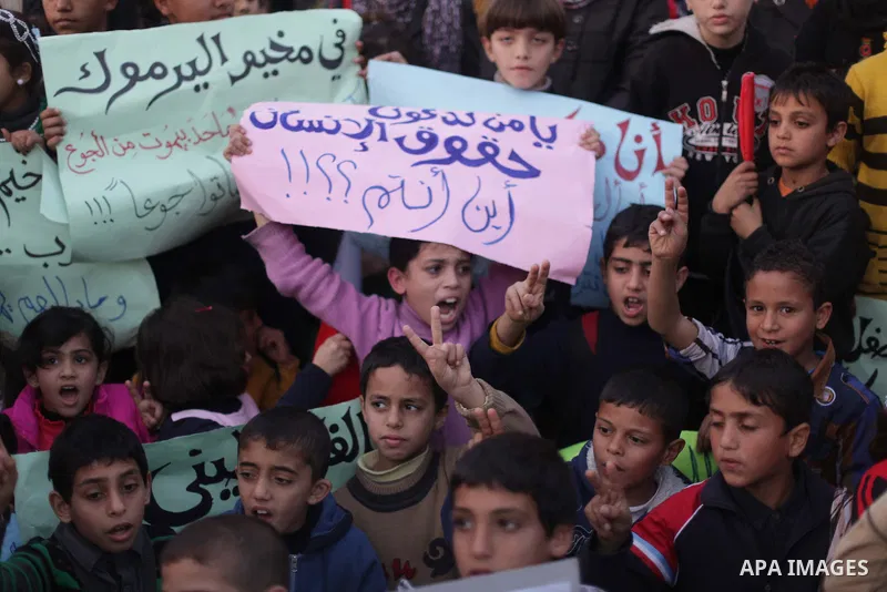 Palestinian children hold placards as they take part in a rally to show solidarity with Palestinian refugees in Syria's main refugee camp Yarmouk, in Deir al-Balah in the central Gaza Strip January 15, 2014. Photo by Ash...