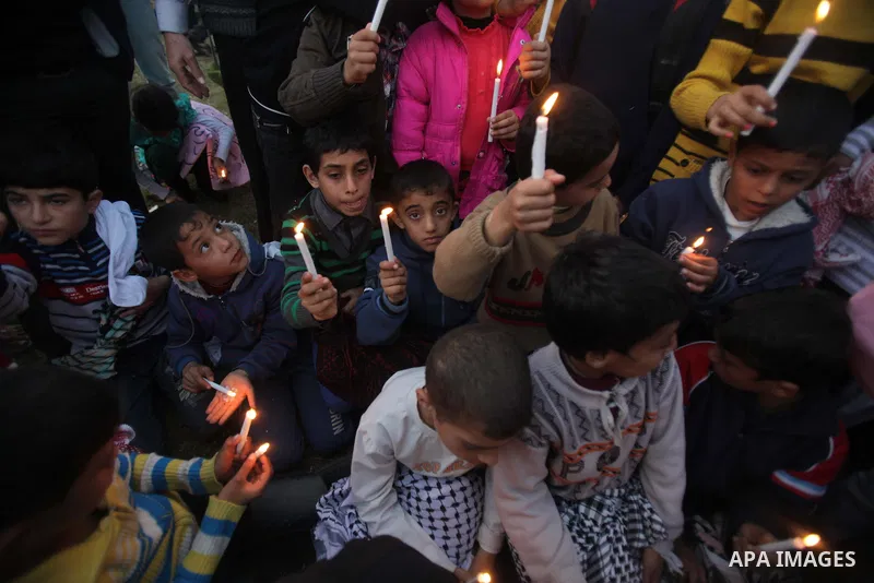 Palestinian children hold candles as they take part in a rally to show solidarity with Palestinian refugees in Syria's main refugee camp Yarmouk, in Deir al-Balah in the central Gaza Strip January 15, 2014. Photo by Ashr...