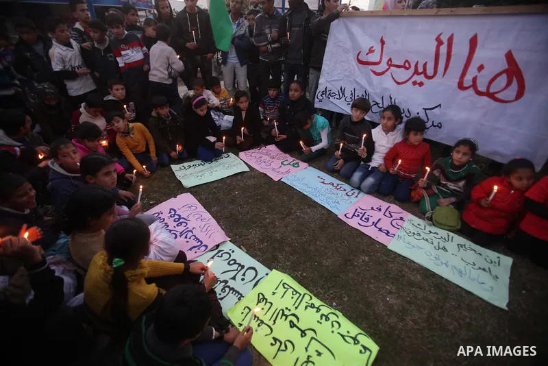 Palestinian children hold candles as they take part in a rally to show solidarity with Palestinian refugees in Syria's main refugee camp Yarmouk, in Deir al-Balah in the central Gaza Strip January 15, 2014. Photo by Ashr...