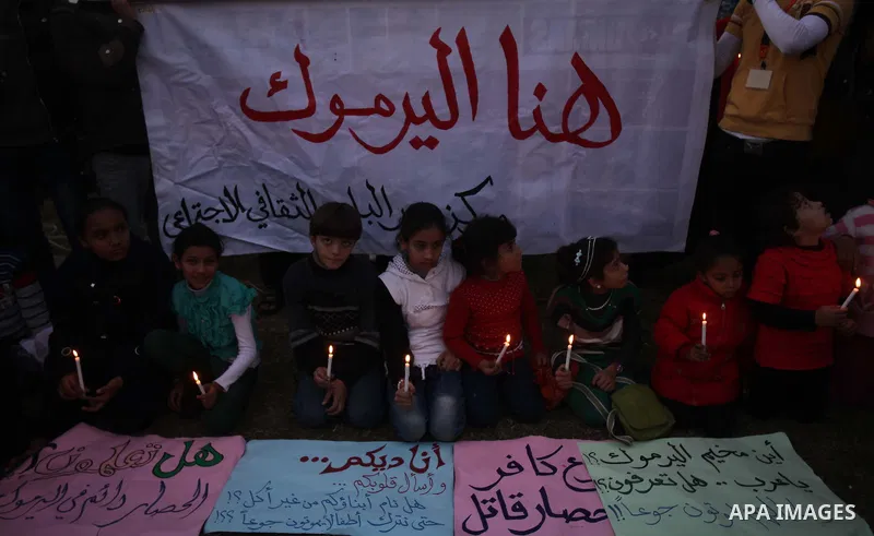 Palestinian children hold candles as they take part in a rally to show solidarity with Palestinian refugees in Syria's main refugee camp Yarmouk, in Deir al-Balah in the central Gaza Strip January 15, 2014. Photo by Ashr...