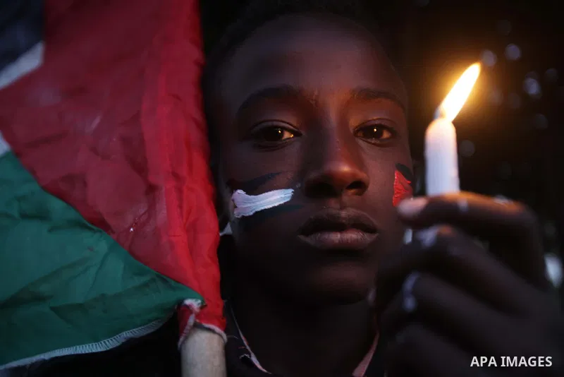 A Palestinian boy holds a candle as he takes part in a rally to show solidarity with Palestinian refugees in Syria's main refugee camp Yarmouk, in Deir al-Balah in the central Gaza Strip January 15, 2014. Photo by Ashraf...