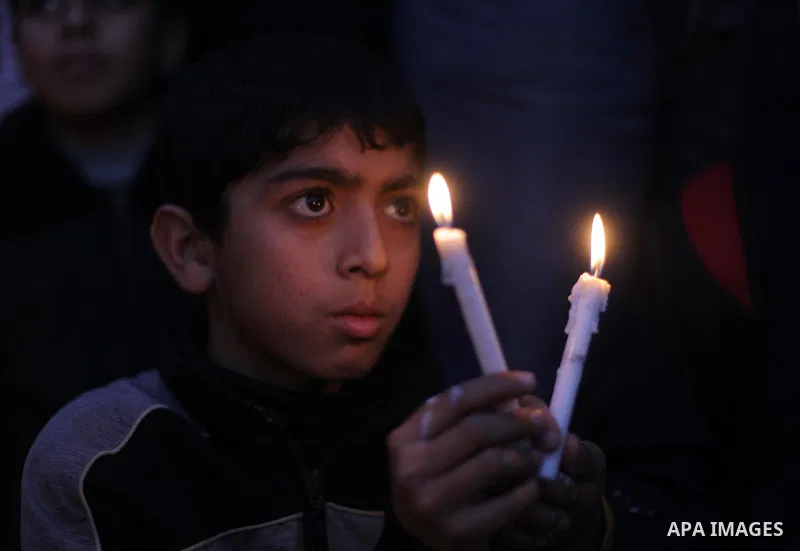 A Palestinian boy holds candles as he takes part in a rally to show solidarity with Palestinian refugees in Syria's main refugee camp Yarmouk, in Deir al-Balah in the central Gaza Strip January 15, 2014. Photo by Ashraf...