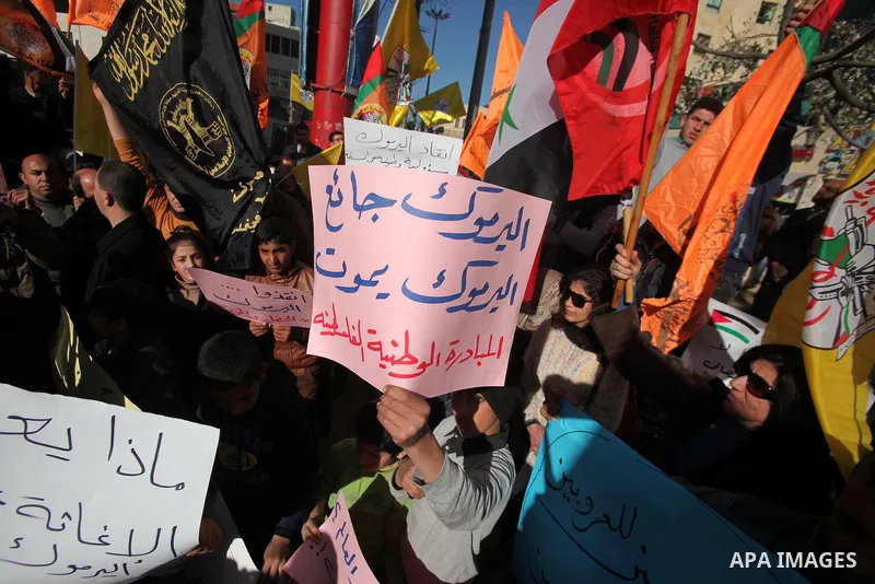 Palestinian protesters wave national and Democratic Front for the Liberation of Palestine flags and hold placards during a demonstration in solidarity with Palestinian refugees in Yarmouk refugee camp in the suburbs of t...